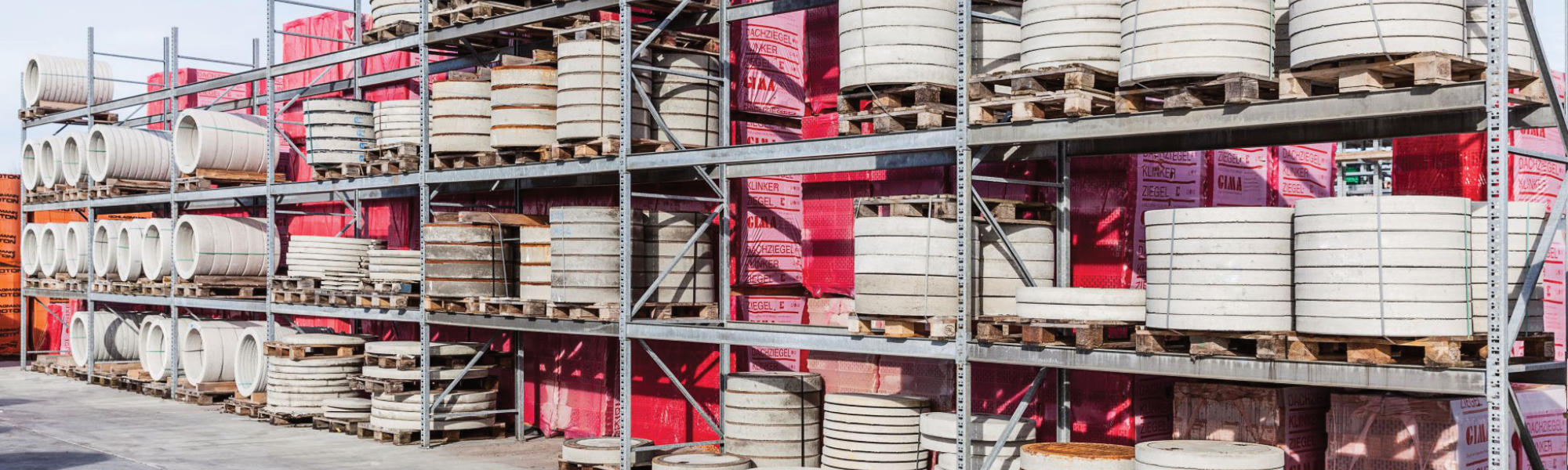 Große Regale mit Betonfertigteilen und pinkfarbenen Paketen dahinter