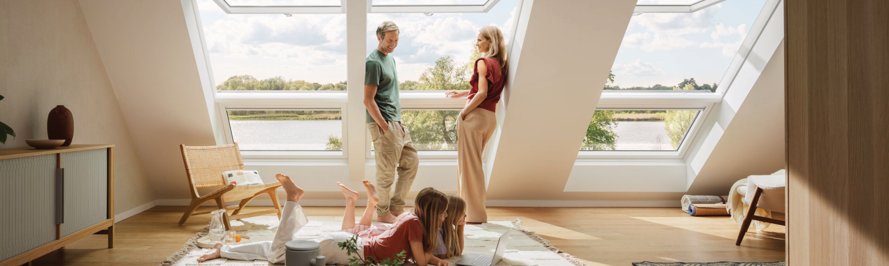 Ein Paar schaut Kindern beim Spielen im Wohnzimmer mit Dachschräge und drei Dachfenstern zu